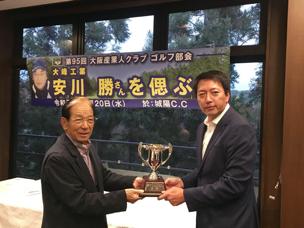 優勝したアジア化成工業所の高田英伸取締役（写真右）と、手渡す山口伊太郎ゴルフ部会長.jpg